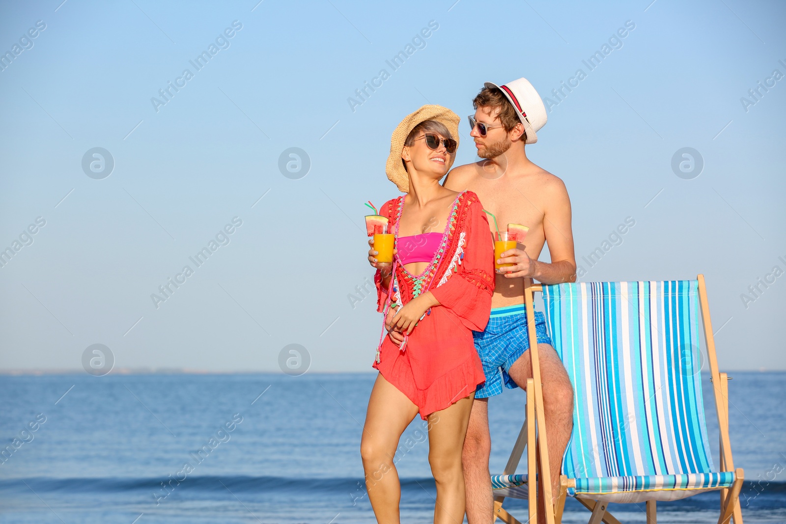 Photo of Young couple with exotic cocktails on beach. Space for text