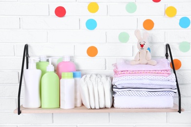 Baby accessories on shelf near white brick wall