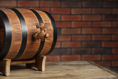 Photo of Wooden barrel with tap on table near brick wall, space for text