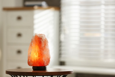 Himalayan salt lamp on table at home, space for text