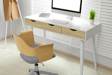 Photo of Stylish office interior with comfortable chair, desk and computer