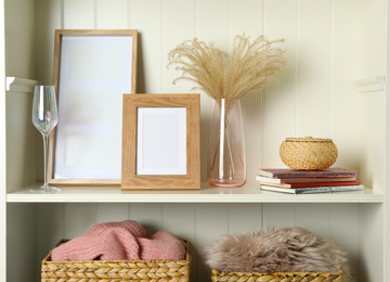 Photo of White shelving unit with photo frames and different decorative elements