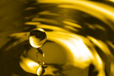 Image of Splash of golden oily liquid with drop as background, closeup. Space for text
