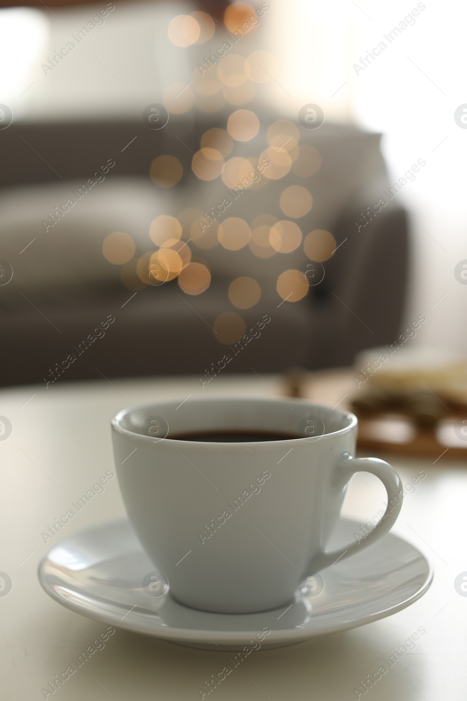 Photo of Cup of aromatic coffee on table indoors. Bokeh effect