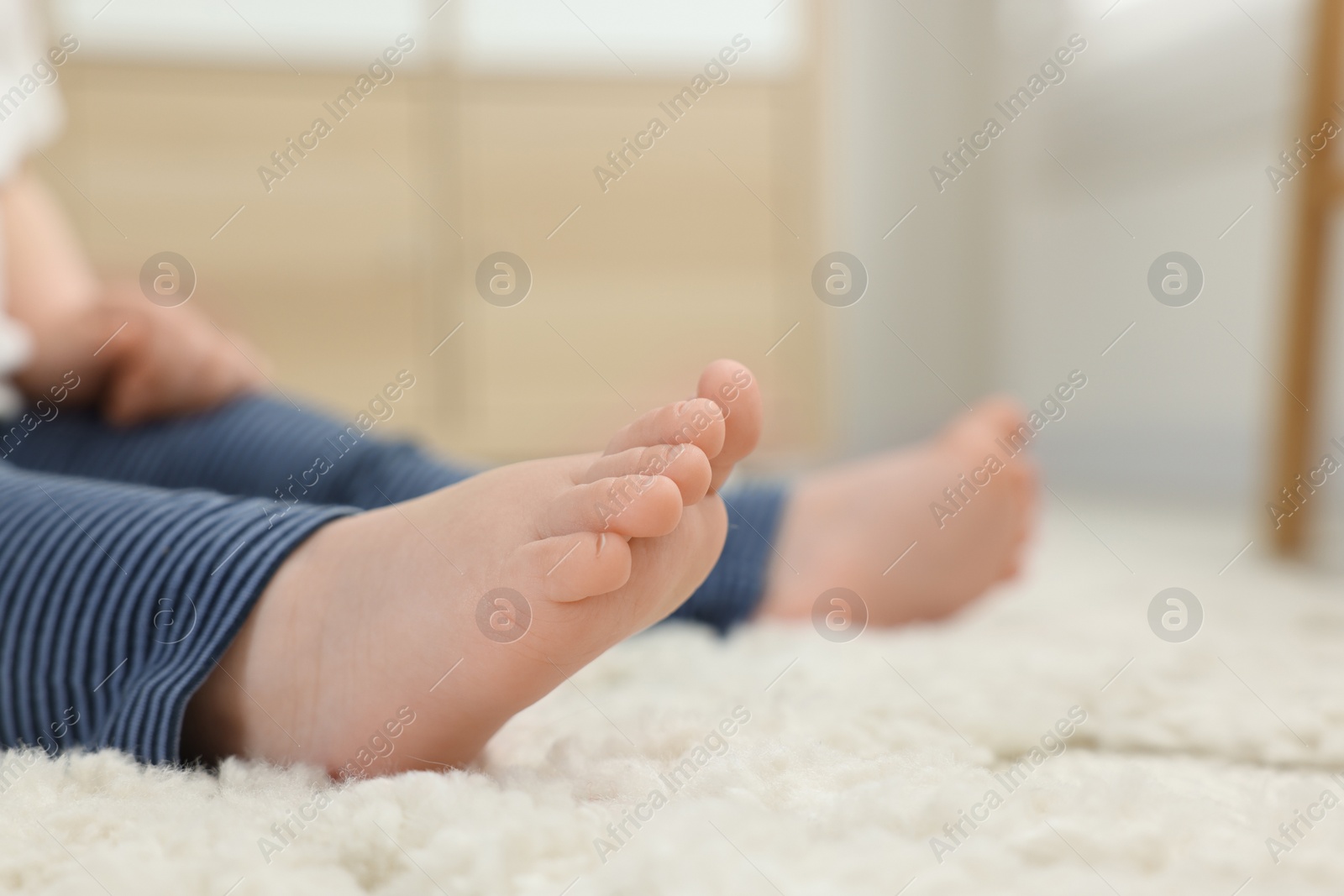 Photo of Baby sitting on soft carpet indoors, closeup. Space for text