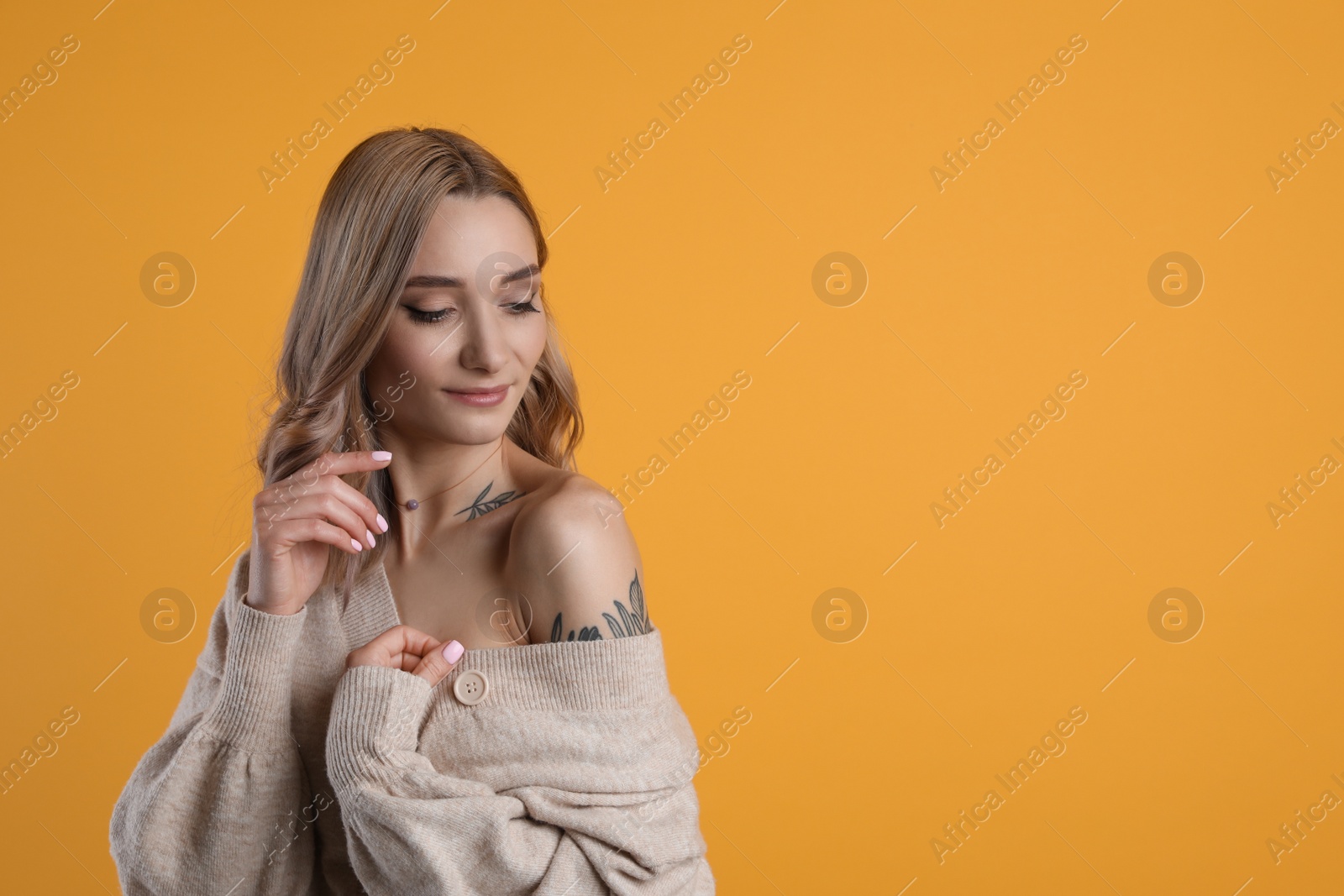 Photo of Beautiful woman with tattoos on body against yellow background. Space for text