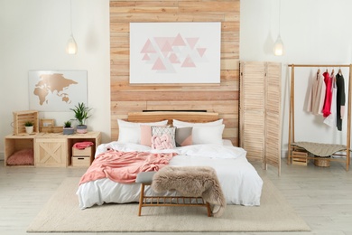 Photo of Stylish room interior with comfortable bed near wooden wall