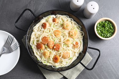 Photo of Delicious scallop pasta with green onion served on grey table, flat lay