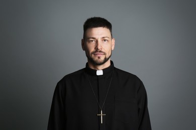 Priest wearing cassock with clerical collar on grey background
