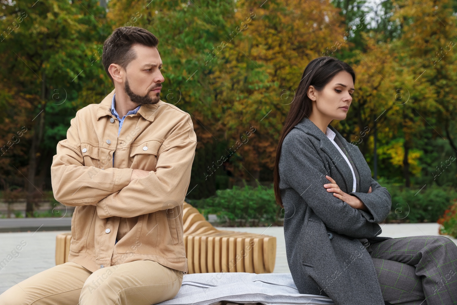 Photo of Upset arguing couple sitting on bench in park. Relationship problems