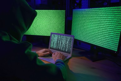 Hacker working with computers at wooden table. Cyber attack