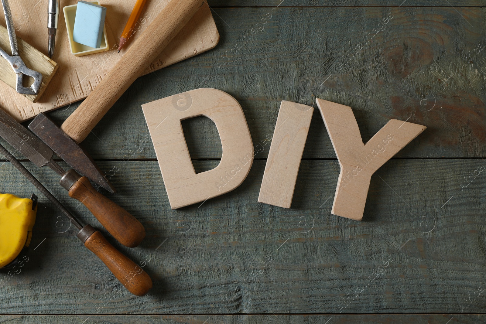 Photo of Abbreviation DIY made of letters and different tools on grey wooden table, flat lay