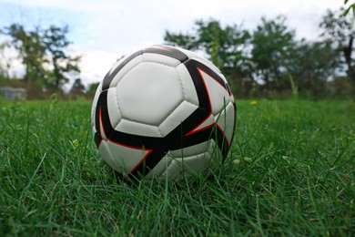 Photo of New soccer ball on fresh green grass outdoors
