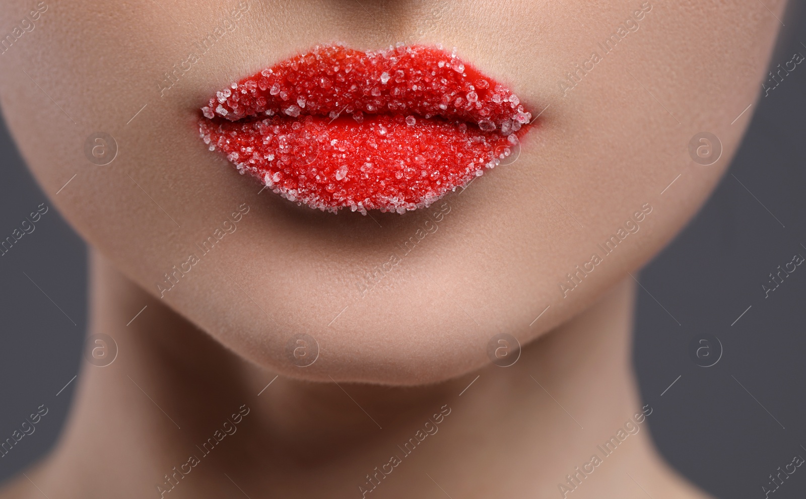 Photo of Woman with beautiful lips covered in sugar on grey background, closeup