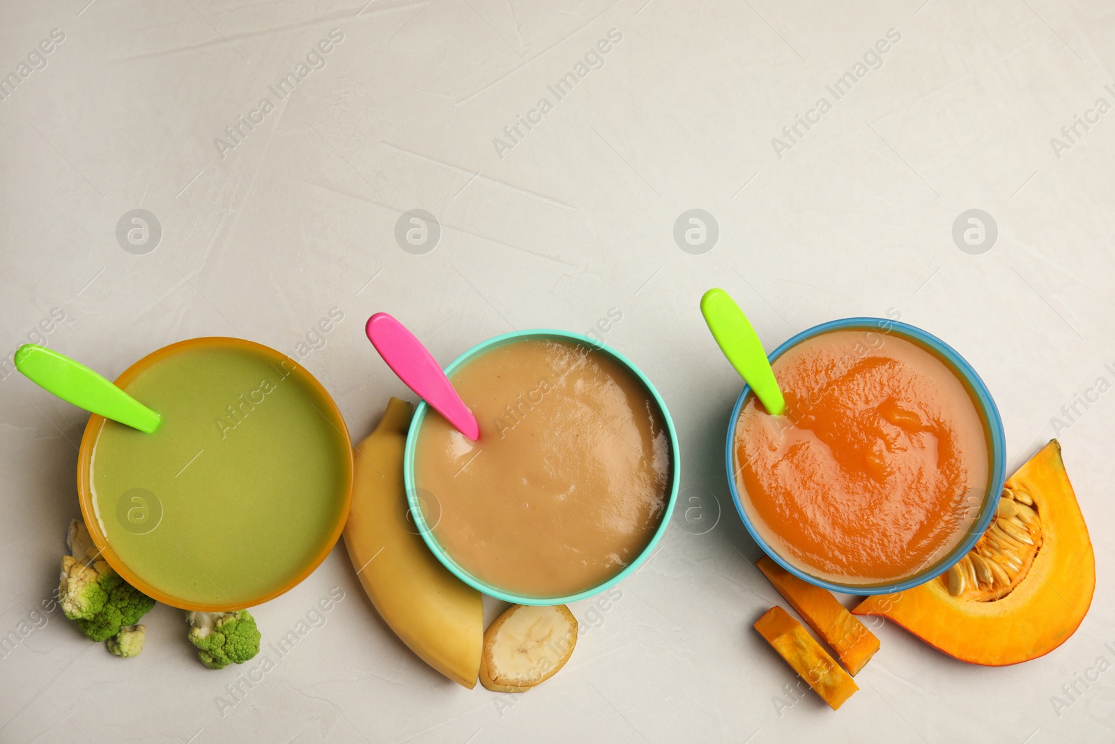 Photo of Bowls with different baby food on gray background, flat lay