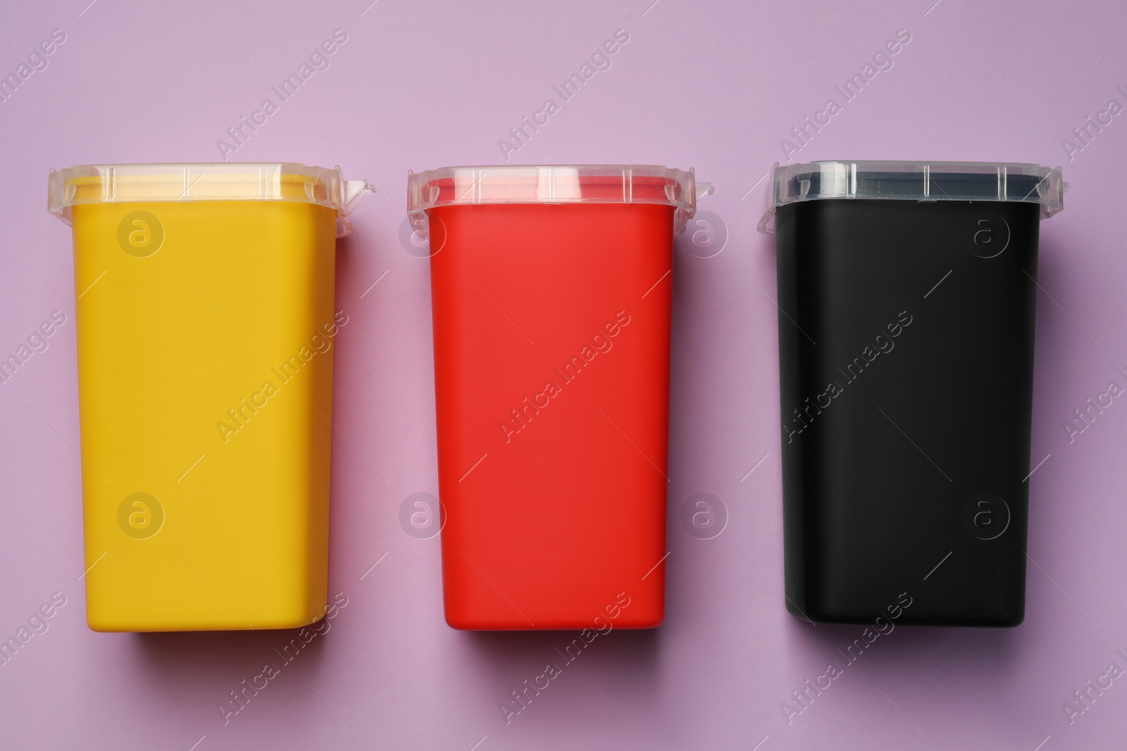 Photo of Sharps containers for used syringe on violet background, flat lay