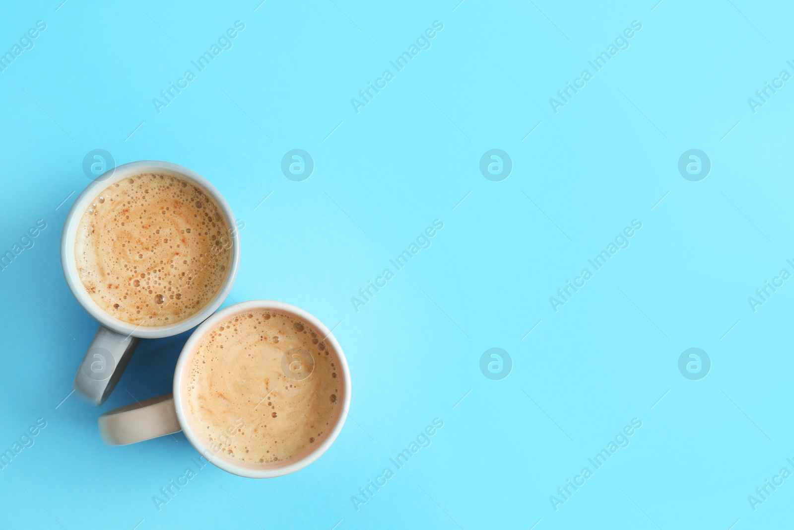 Photo of Cups of coffee on blue background, top view. Space for text