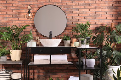 Stylish bathroom interior with modern sink, furniture and beautiful green houseplants