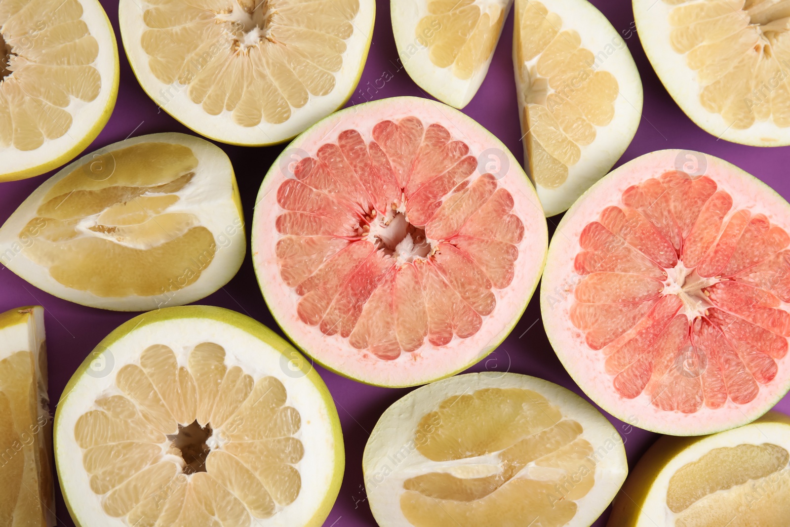 Photo of Fresh cut pomelo fruits on purple background, flat lay