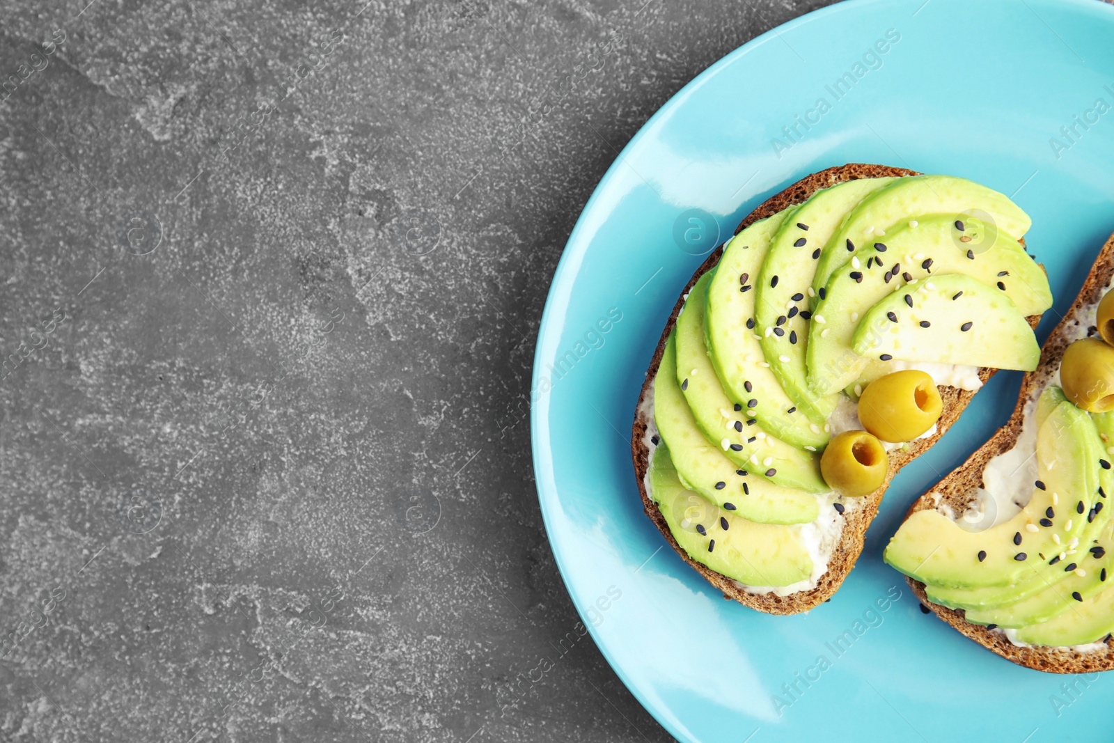 Photo of Crisp rye toasts with avocado, cream cheese and olives on plate, top view