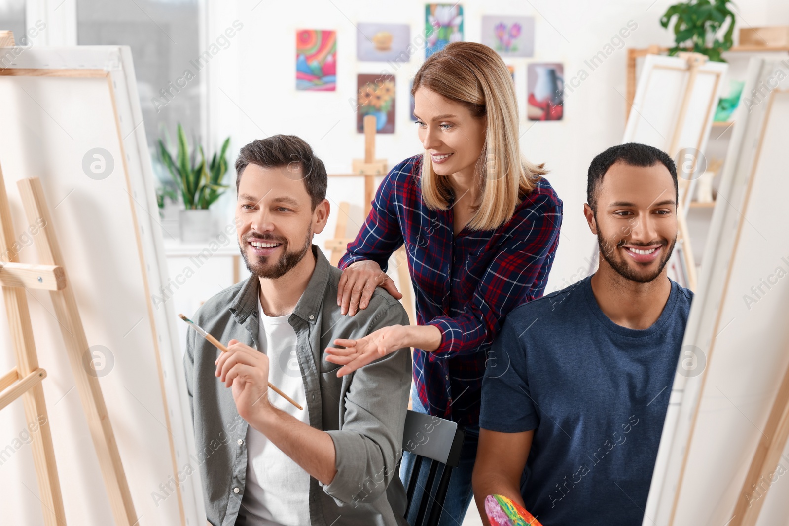 Photo of Artist teaching her students to paint in studio. Creative hobby