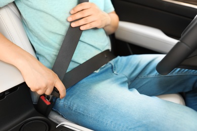 Male driver fastening safety belt in car, closeup