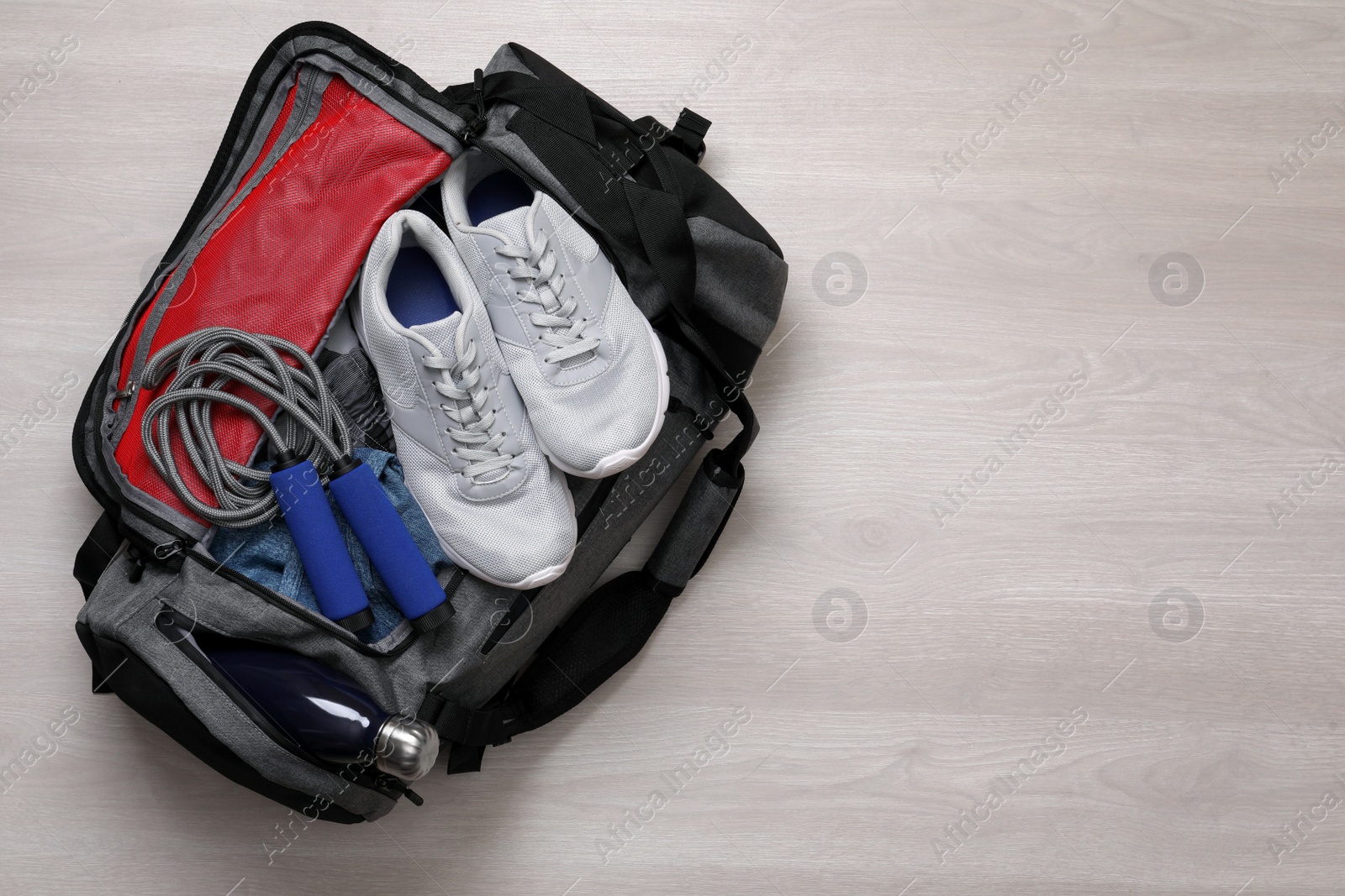 Photo of Gym bag with sports equipment on wooden background, top view