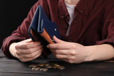 Photo of Poverty. Woman with empty wallet and coins at wooden table, closeup