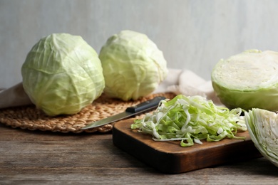 Photo of Whole and shredded cabbage on wooden table