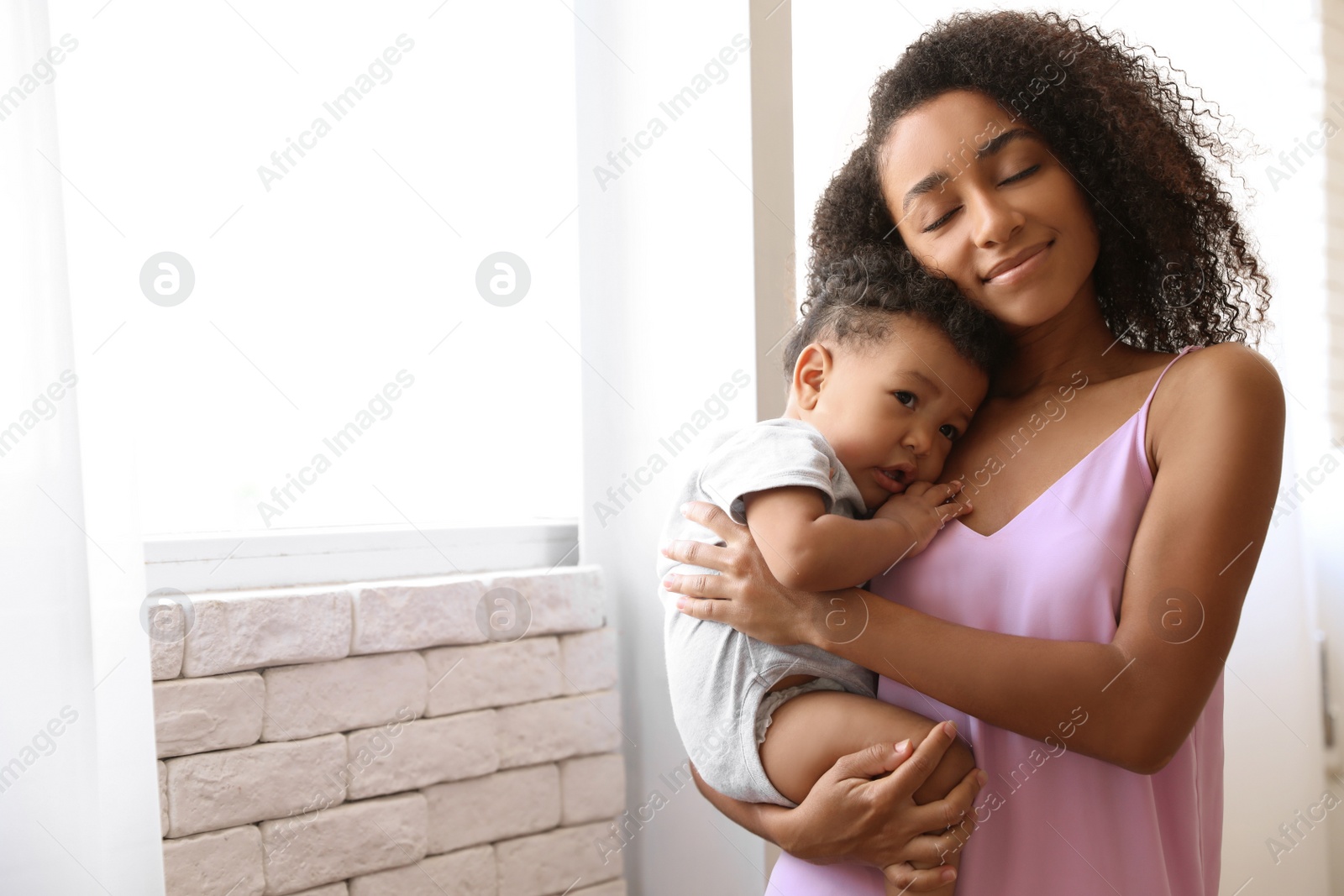 Photo of African-American woman with her baby at home. Happiness of motherhood