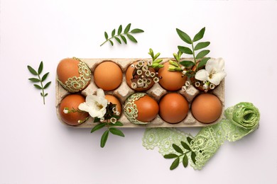 Flat lay composition with Easter eggs, twigs and lace ribbon on white background