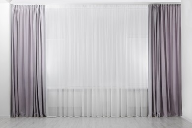 Photo of Light grey window curtains and white tulle indoors