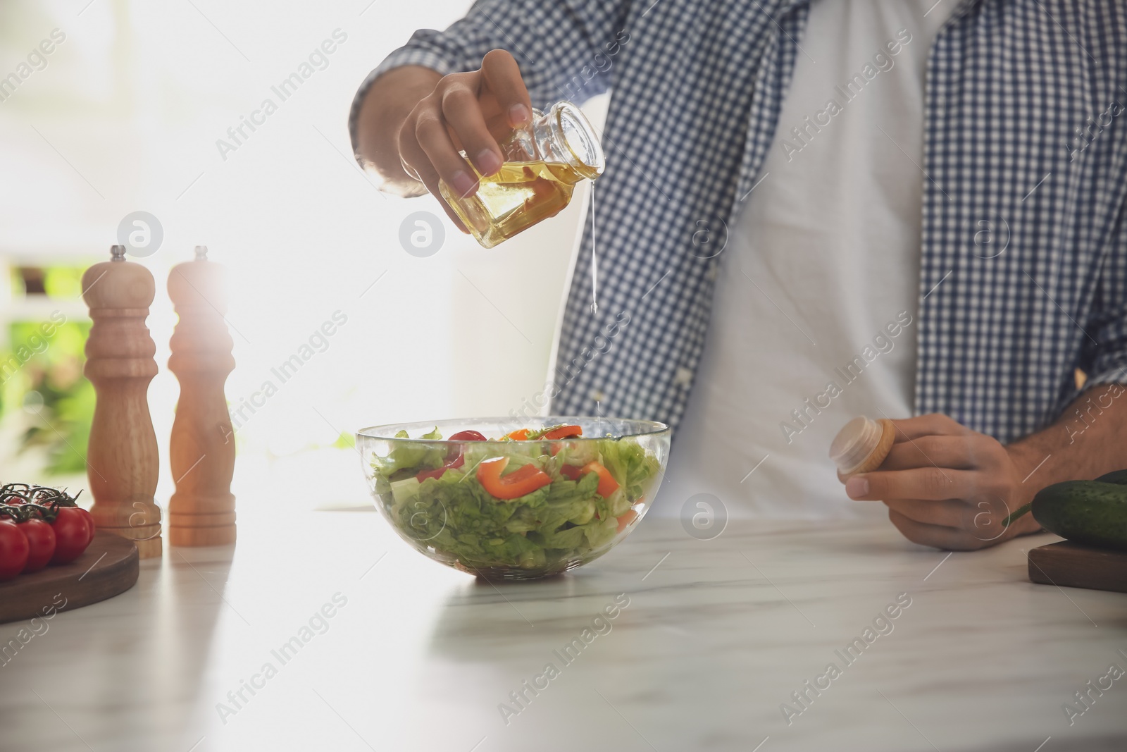 Photo of Man cooking salad at table in kitchen, closeup