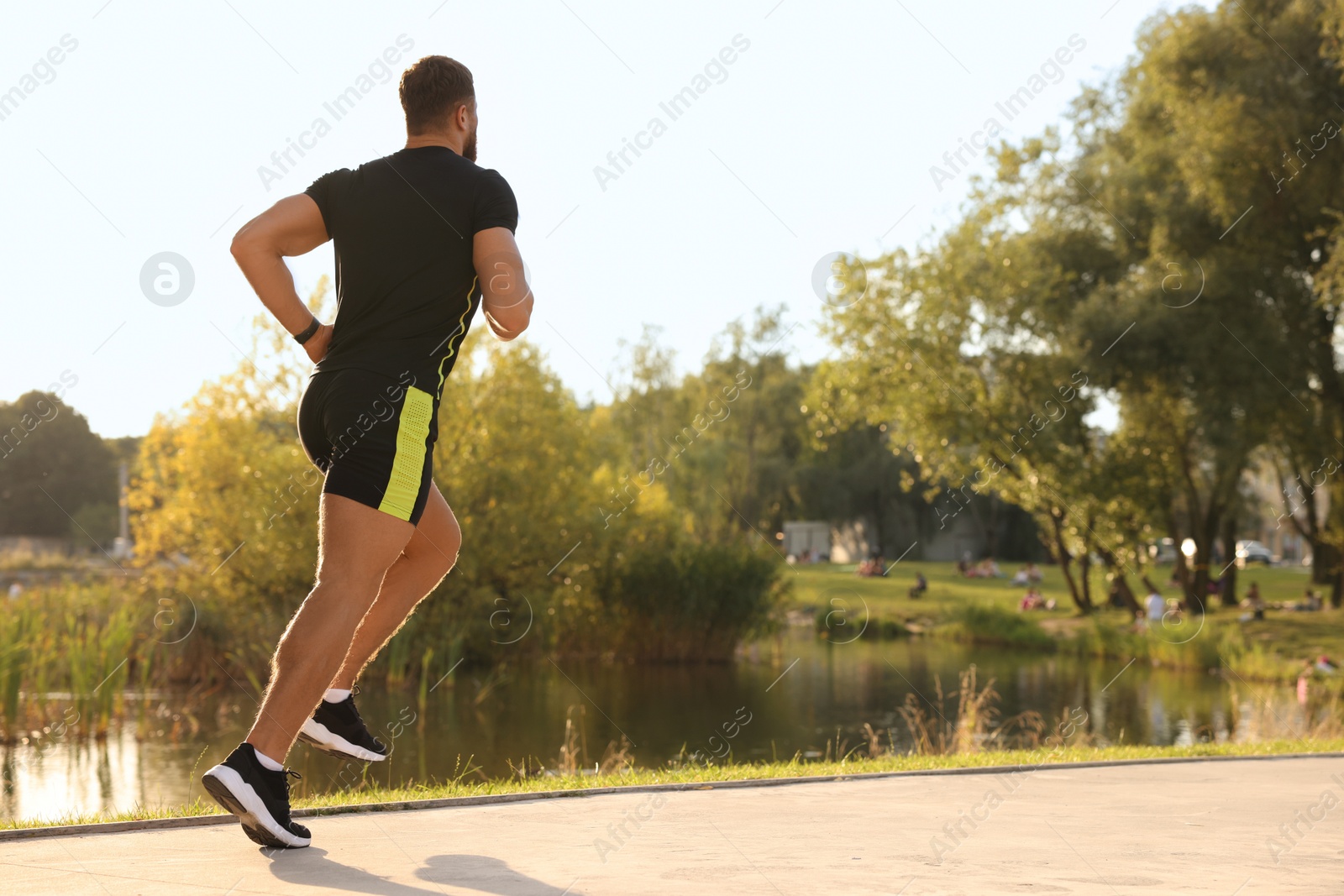 Photo of Man running near pond in park. Space for text