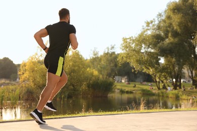 Man running near pond in park. Space for text