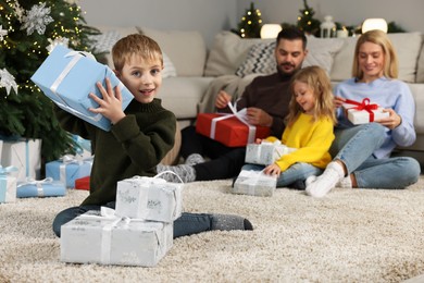 Photo of Family Christmas celebration. Little boy with gift at home, selective focus