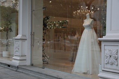 Photo of Showcase with beautiful wedding dress on mannequin