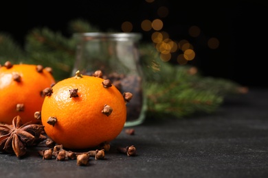 Photo of Delicious fresh tangerines with cloves on black table. Christmas celebration