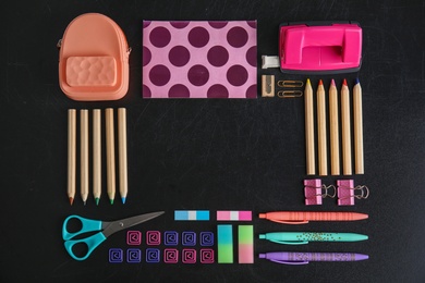 Flat lay composition with different school stationery on chalkboard surface