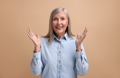 Portrait of emotional middle aged woman on beige background