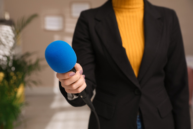Photo of Professional journalist with modern microphone in room, closeup