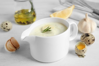 Photo of Composition with ceramic jug of garlic sauce on wooden table