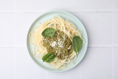 Photo of Tasty pasta with spinach, cheese and sauce on white tiled table, top view