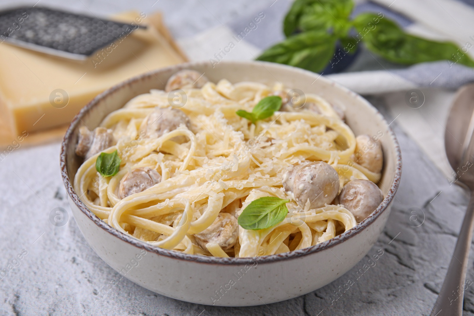 Photo of Delicious pasta with mushrooms and cheese on light grey textured background, closeup