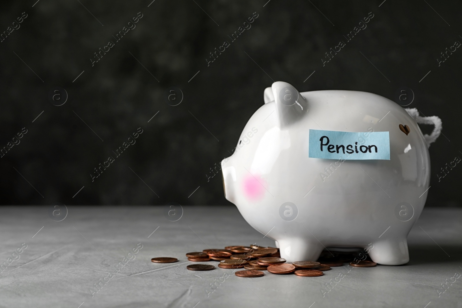 Photo of Piggy bank with word PENSION and coins on table. Space for text