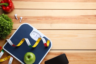 Photo of Flat lay composition with bathroom scale and measuring tape on wooden floor, space for text. Weight loss concept