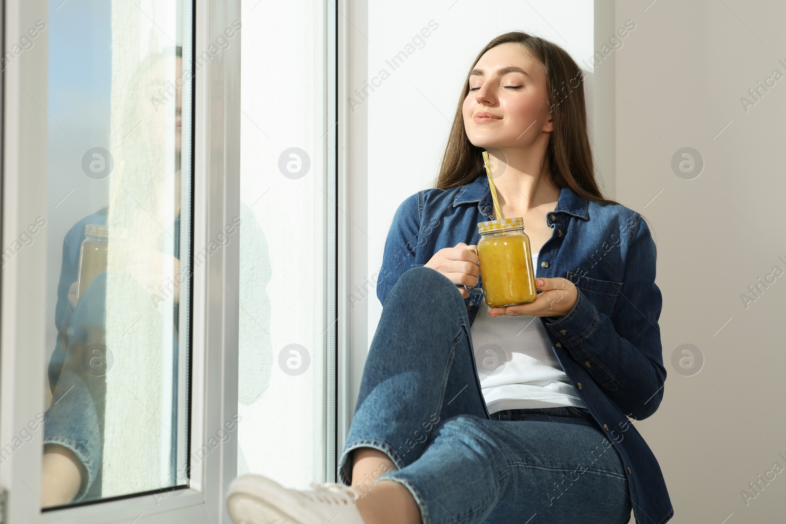 Photo of Beautiful young woman with delicious smoothie near window. Space for text