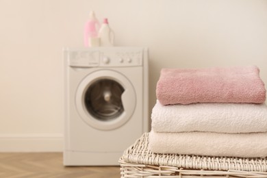 Clean folded towels on wicker basket in laundry room. Space for text