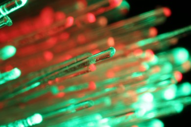 Optical fiber strands transmitting different color lights in darkness, macro view
