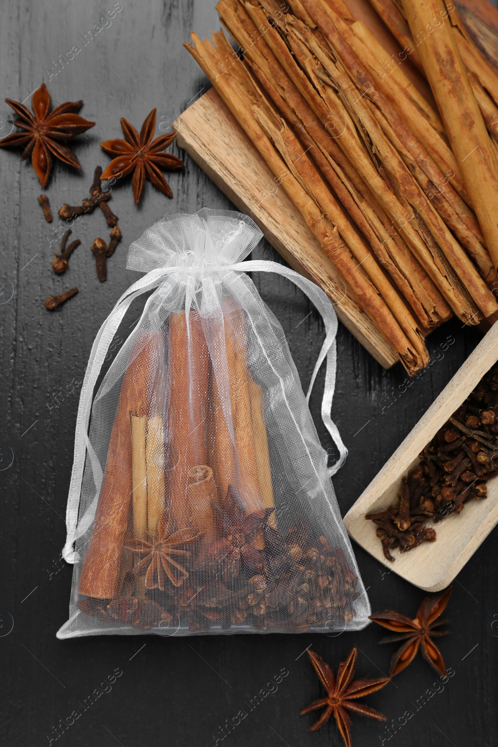 Photo of Scented sachet with cinnamon sticks and anise stars on wooden table, flat lay